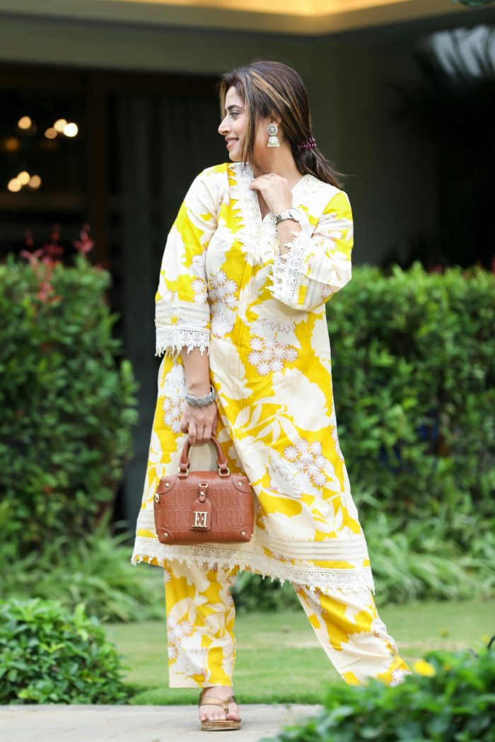 Elegant woman in a vibrant yellow floral kurta, enjoying a sunny day outdoors in Bengaluru.